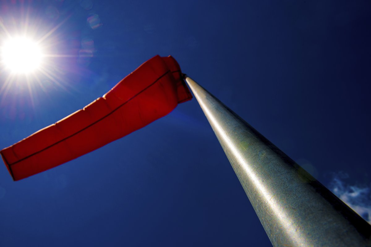 UV-weathered windsock backlit by the sun, showing fabric fatigue